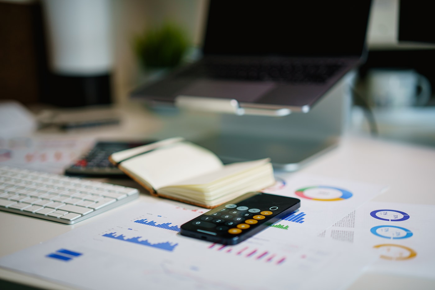 Accountant's desk with laptop, calculator, notebook, and printed financial charts
